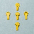 A set of five white self adhesive hooks displayed on a clean surface.