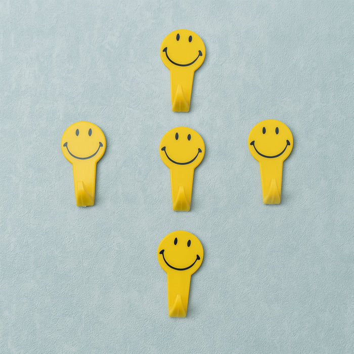 A set of five white self adhesive hooks displayed on a clean surface.