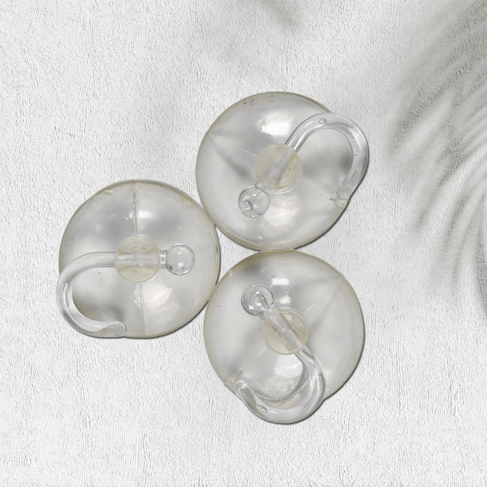 Two transparent suction hooks with strong hold on a bathroom tile wall.